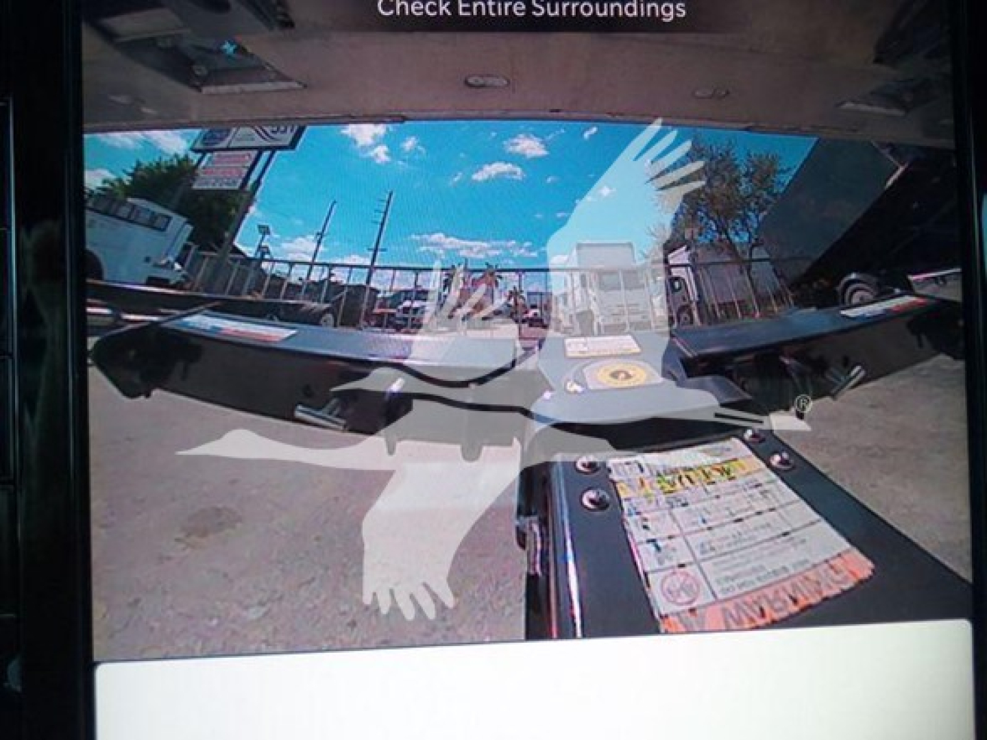 Truck rollback bed view with hitch components and label placard, showing the interior frame and rear cab window reflection.