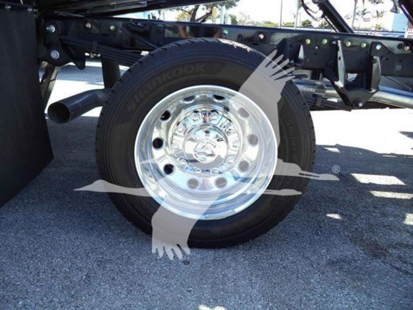 Truck wheel and chrome hubcap showing Hankook tire on a rollback chassis with visible frame.