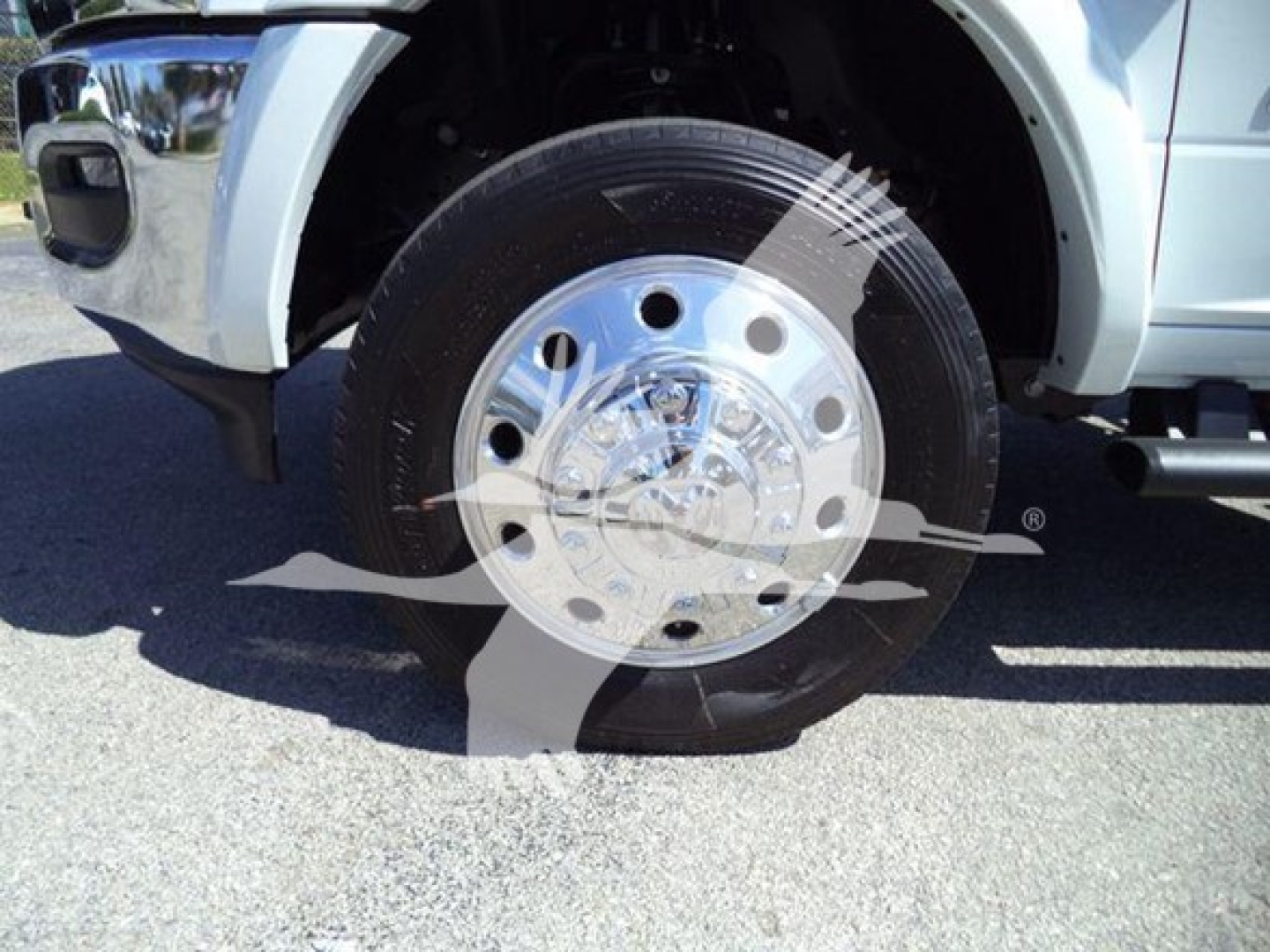 Truck front wheel and chrome hubcap with tire. Visible text on hubcap too small to read clearly.