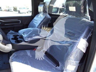 Ram pickup truck interior showing front seats in plastic covering and center console with cup holders; light gray/black color scheme; steering wheel on left side.