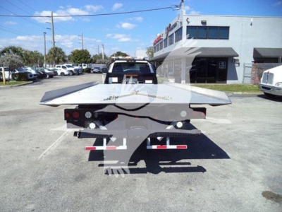 Truck bed on a rollback trailer with a flatbed and rear lights visible.