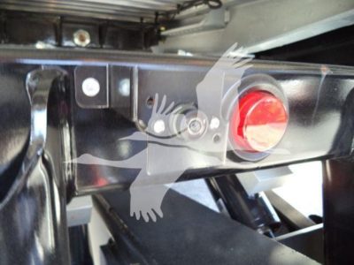 Truck hitch area showing towing hitch frame with a red round access plug and metal mounting brackets.