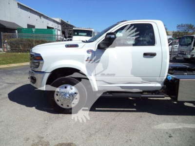 Ram pickup truck side view showing white exterior and large dual rear wheels on rollback.