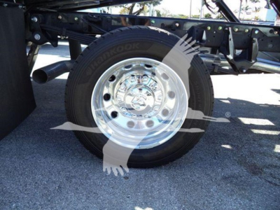 Truck wheel and chrome hubcap showing Hankook tire on a rollback chassis with visible frame.