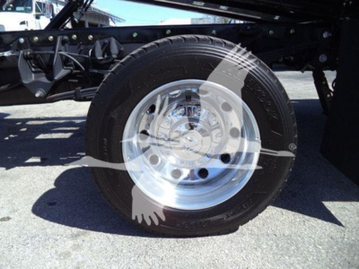 Truck wheel and tire assembly showing polished chrome hubcap and black tire underframe with bolts and suspension components visible.