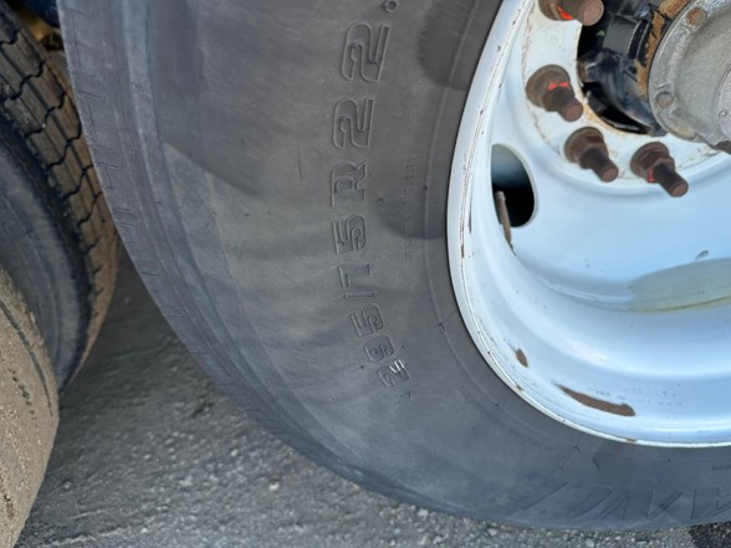 Flatbed trailer wheel and tire close-up showing wheel hub and stamped tire size markings