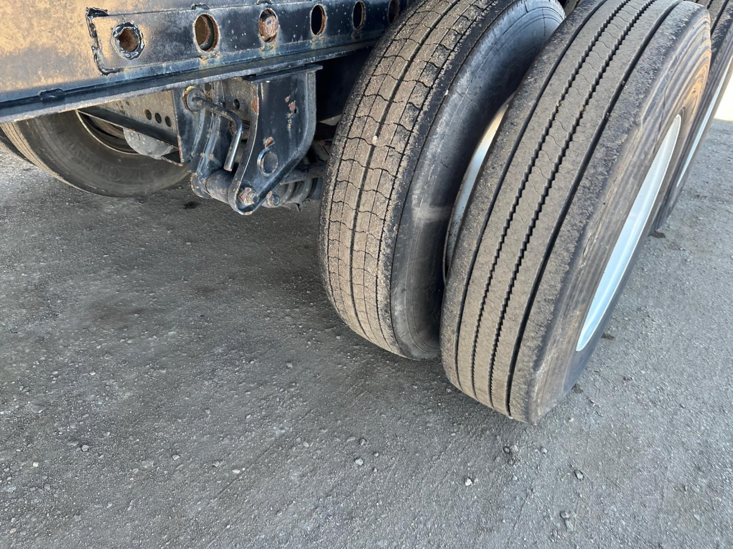 Trailer axle with dual tires and undercarriage visible; no legible sticker text visible on the photo itself.