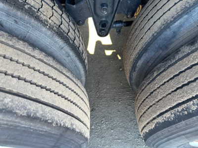 Trailer axle dual tires view in the wheel well showing tread and suspension components.