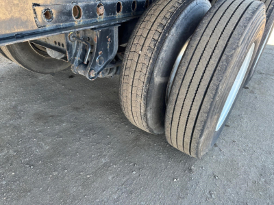 Trailer axle with dual tires and undercarriage visible; no legible sticker text visible on the photo itself.