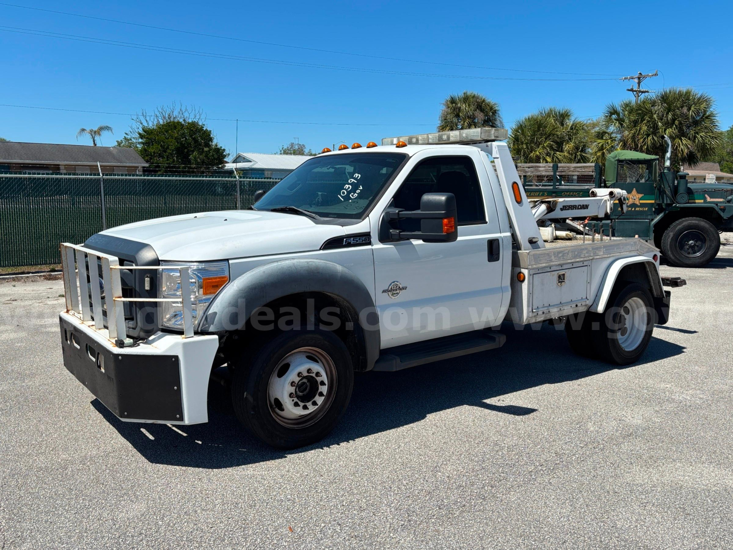 Ford F-550 tow truck 2012 model, white cab with flatbed, front grille chrome, black bumper guard, service lights on roof, driveline and wheel details visible