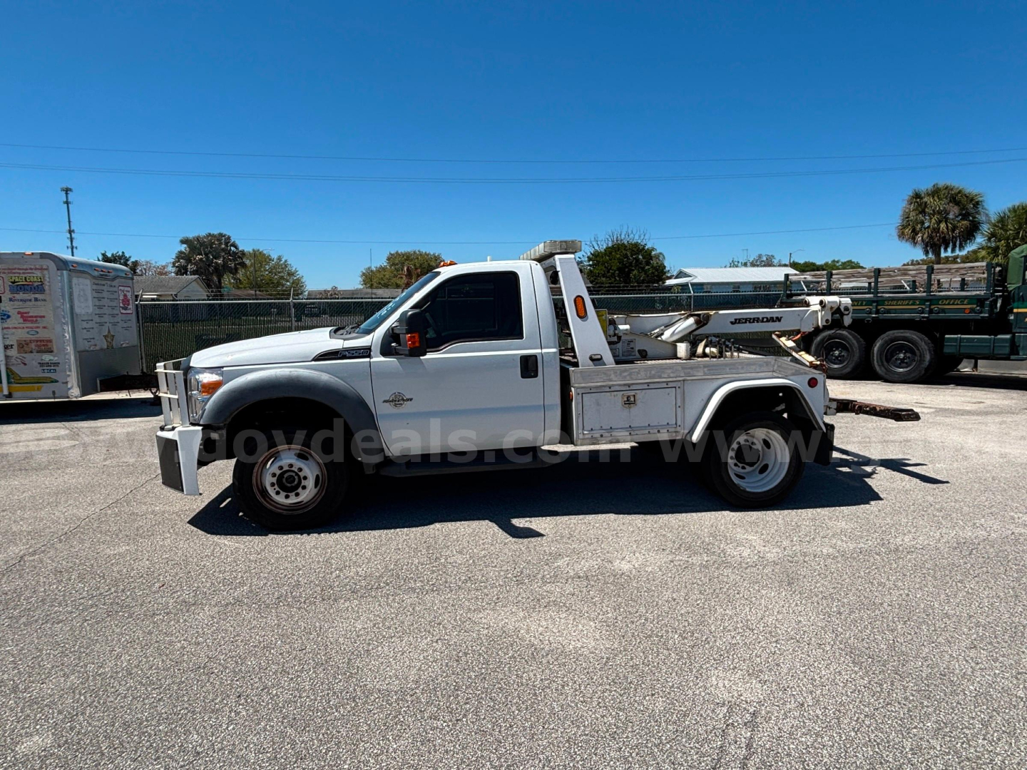 Ford F-550 tow truck in serviceable condition shown from side profile with flatbed and equipment rack.