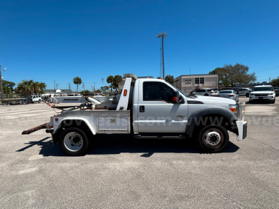Tow truck mounted with wheel lift in side profile view of a 2012 Ford F-550 used vehicle with white cab and aluminum utility bed.