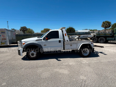 Ford F-550 tow truck in serviceable condition shown from side profile with flatbed and equipment rack.