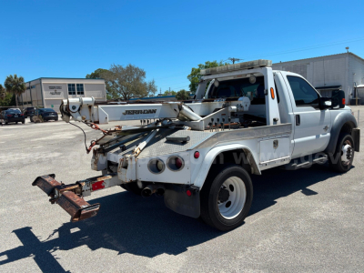 Tow truck with mounted crane/boom in rear and hitch, Ford F-550 utility/service truck, side view showing crane and rear equipment.