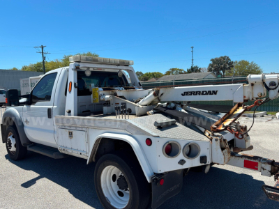 Ford F-550 tow truck with Jerr-Dan wrecking boom in service bay showing rear hitch and tool compartments.