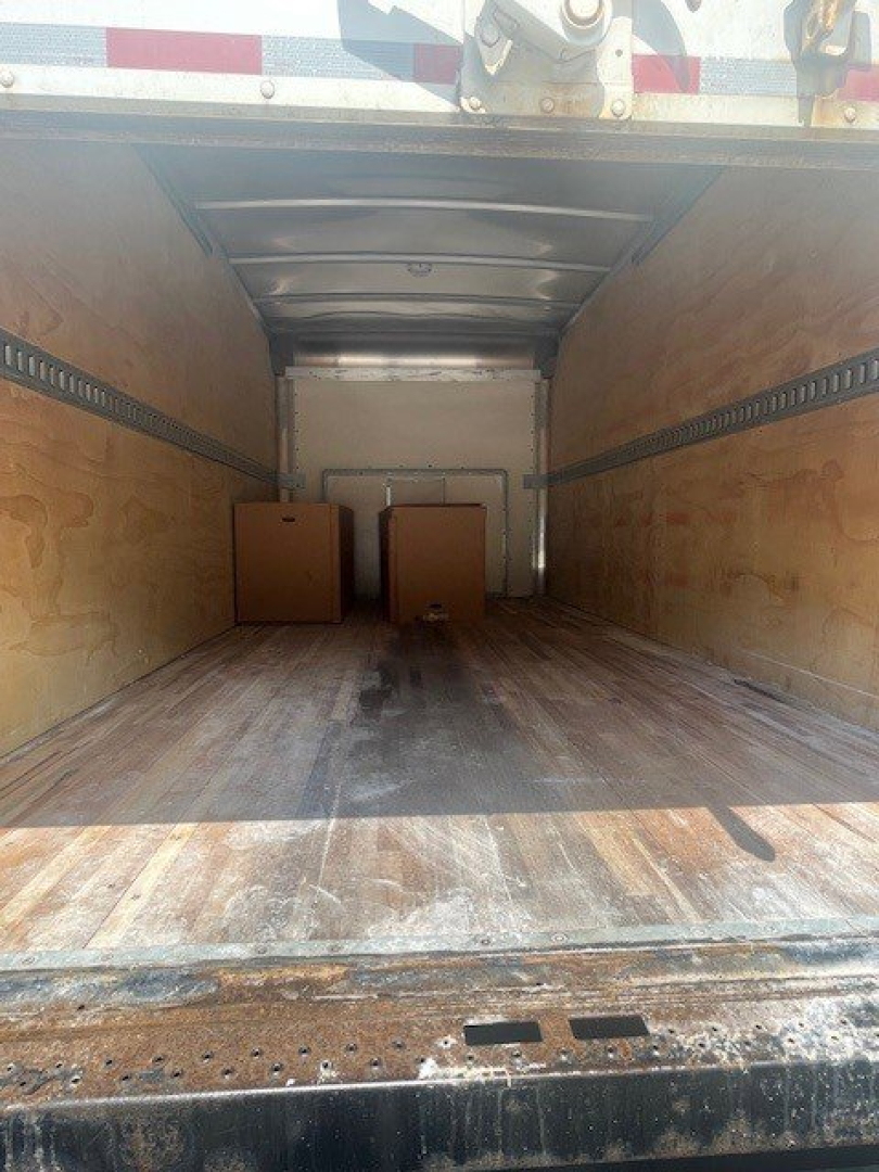 Interior cargo area of a 2019 Ford E-Series Cutaway Cab Chassis truck showing wooden sidewalls and a couple of boxes in the cargo bay.