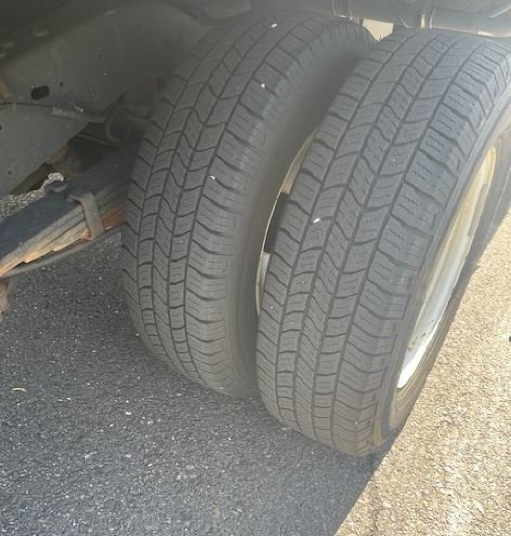 Dual rear wheels of a 2019 Ford E-Series Cutaway truck showing tire treads and part of the suspension.