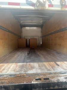 Interior cargo area of a 2019 Ford E-Series Cutaway Cab Chassis truck showing wooden sidewalls and a couple of boxes in the cargo bay.