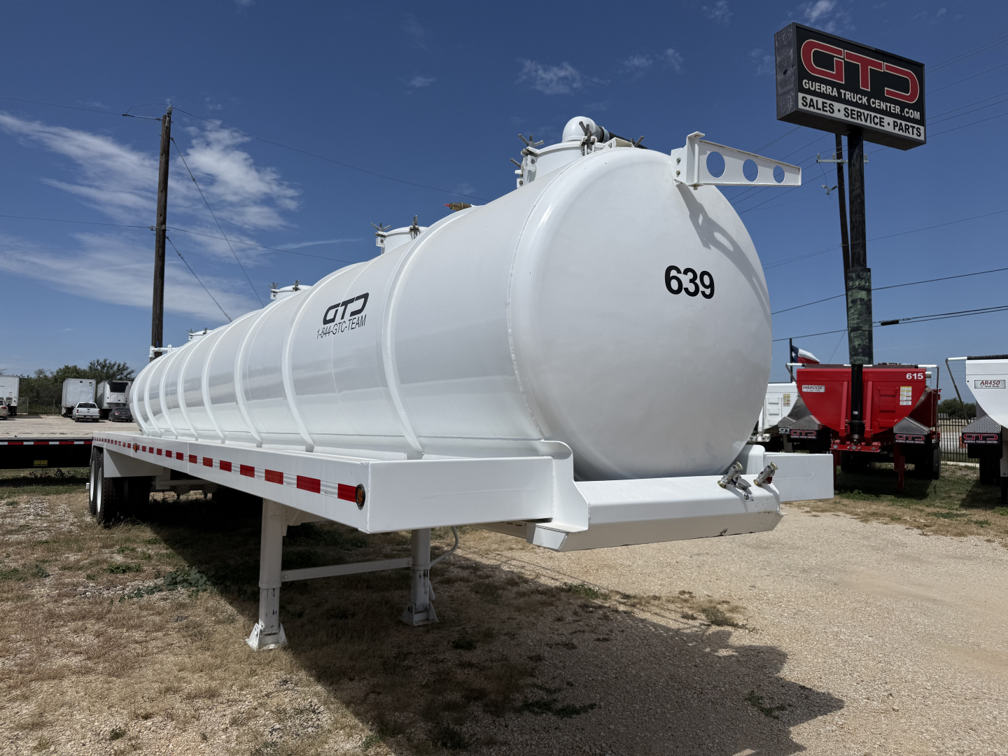 Tank trailer with white cylindrical tank on a trailer frame; number 639 on front head; GP Iron Lite logo on side; outdoor lot with blue sky and signboard.