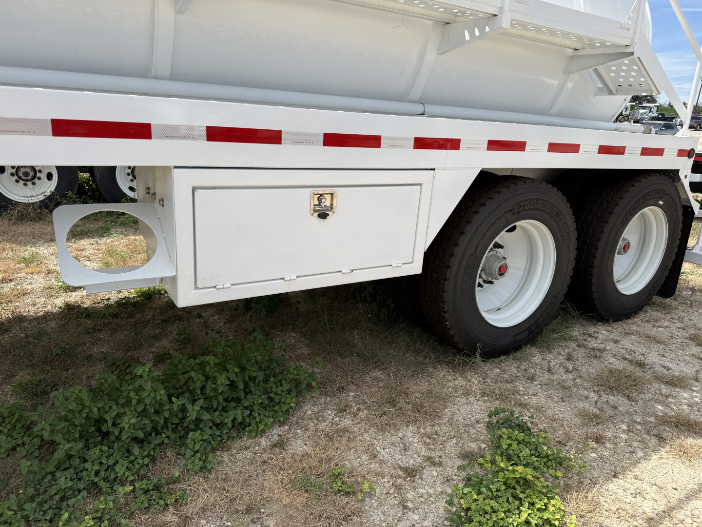 Trailer side view showing storage box undertank and dual rear wheels on a white Iron Lite VAC130 trailer.