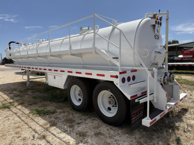 Tank trailer shown from rear-left side with white cylindrical tank on dual-axle chassis, railing along top, rear access steps, and red/white safety stripes.