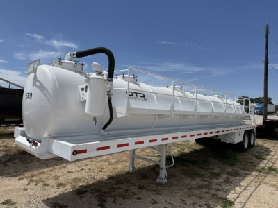 Trailer-mounted vacuum tanker tank showing white cylindrical vessel with raised hatch and black hose, side rails, support legs, and dual-axle undercarriage.