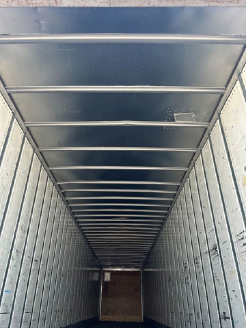 Interior view of a rectangular trailer with metal ribbed walls and ceiling, showing the long narrow cargo space.