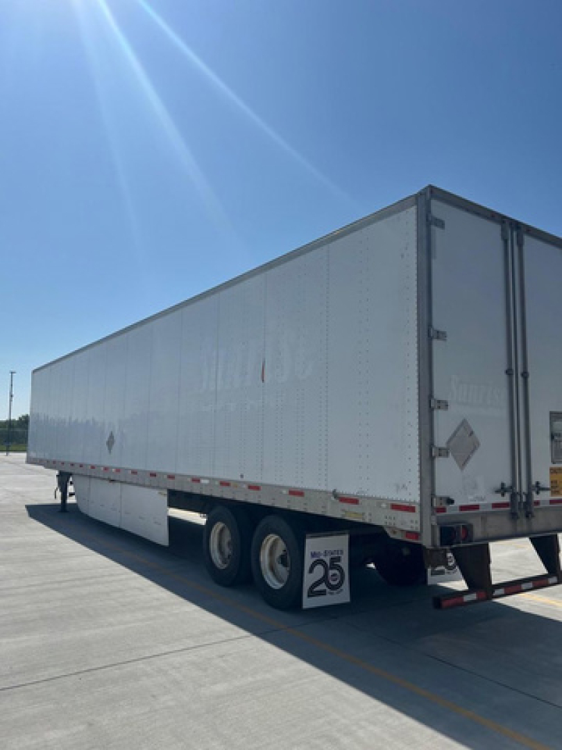 Trailer body of a 2013 utility van trailer showing smooth riveted aluminum sides and dual rear doors.