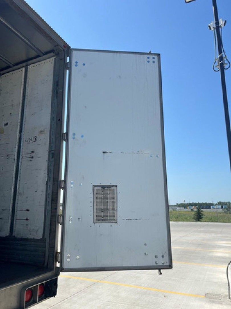 Utility van interior cargo area with open rear door showing metal panel and ventilation grate.