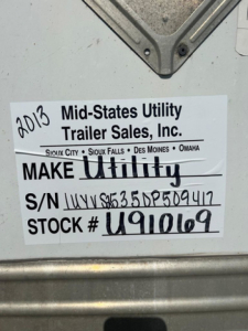 Label on trailer rear showing 2013 Mid-States Utility Trailer Sales, Inc. Make Utility S/N UYVS... ST0CK # U910169? Serial number and stock number handwritten.