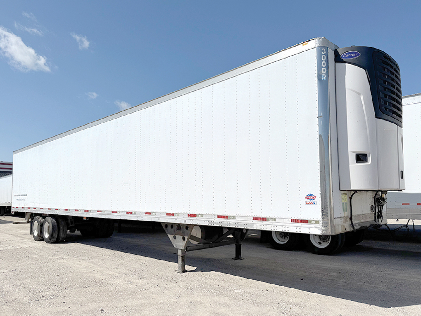 Utility 3000R refrigerated trailer with white insulated body and Carrier reefer unit at front; side view showing landing gear and dual rear axles.