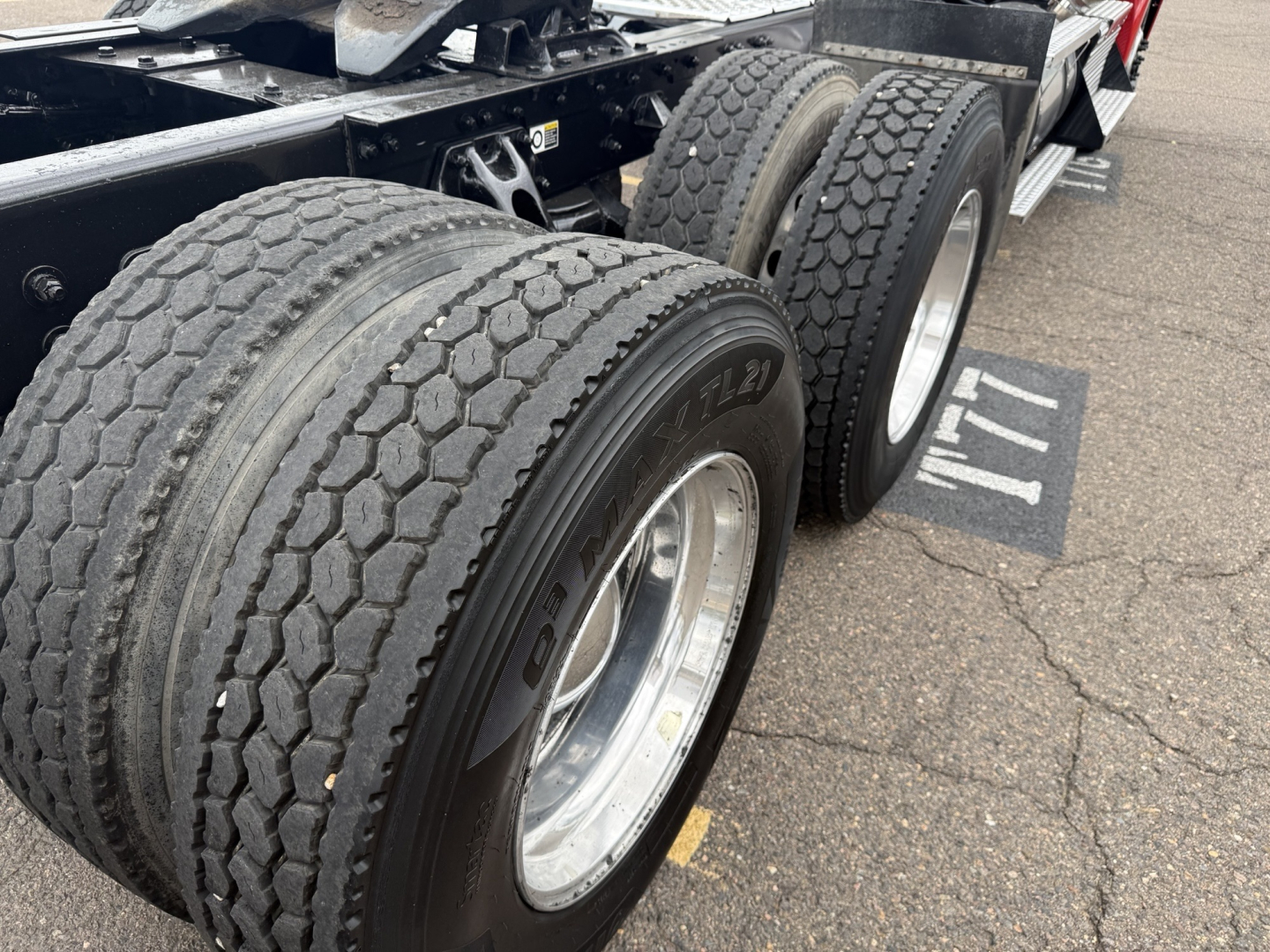 Kenworth T880 chassis showing dual rear axles with large tires and wheel rims, section of frame and fifth wheel visible.