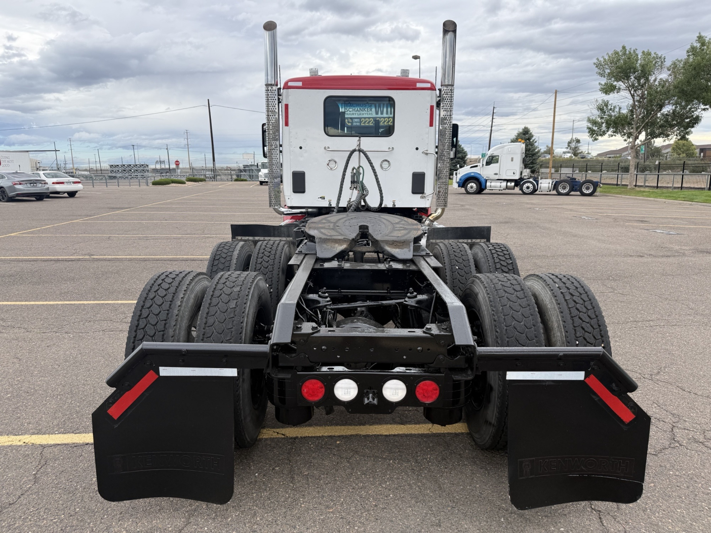Kenworth T880 rear view showing dual rear axles, white cab, black chassis, mud flaps, and rear lights. No license plate.