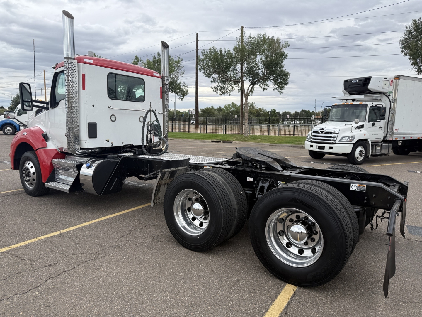Kenworth T880 tractor cab with exposed chassis and dual rear axles, red and white cab, in a parking lot.