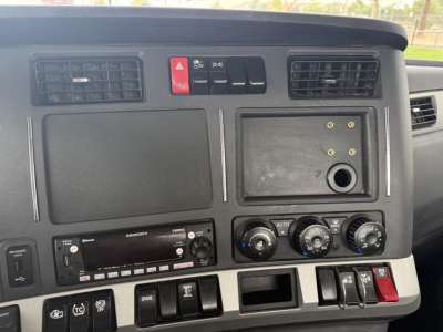 Dashboard of 2023 Kenworth T880 showing climate controls, hazard switch, vents, and radio in-dash panel.
