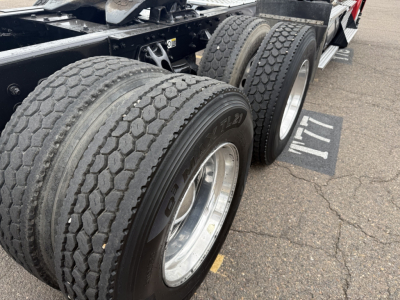 Kenworth T880 chassis showing dual rear axles with large tires and wheel rims, section of frame and fifth wheel visible.