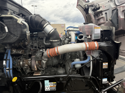 Kenworth T880 engine bay showing large turbo intake, fluid reservoirs, hoses, and label stickers