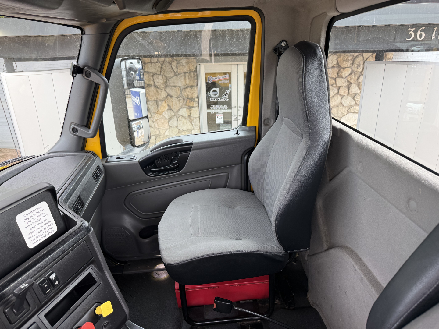 Truck cab interior view showing driver seat and dashboard of a 2019 International LT with yellow door frame. Visible text on dashboard and side panels not fully legible.
