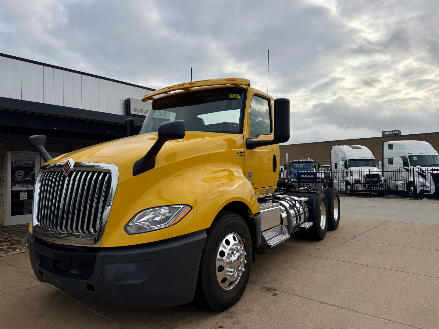 Yellow 2019 International LT conventional daycab truck in a dealership lot, side view showing front grille, headlights, dual rear axles, and mirror extensions.