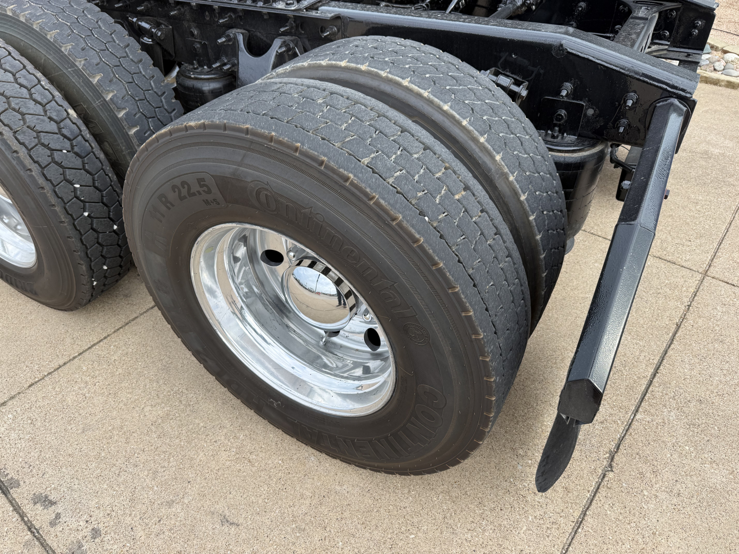 Truck rear dual tires and spring suspension of a 2019 International LT, showing dual rear wheels and chrome rims with rubber tires.