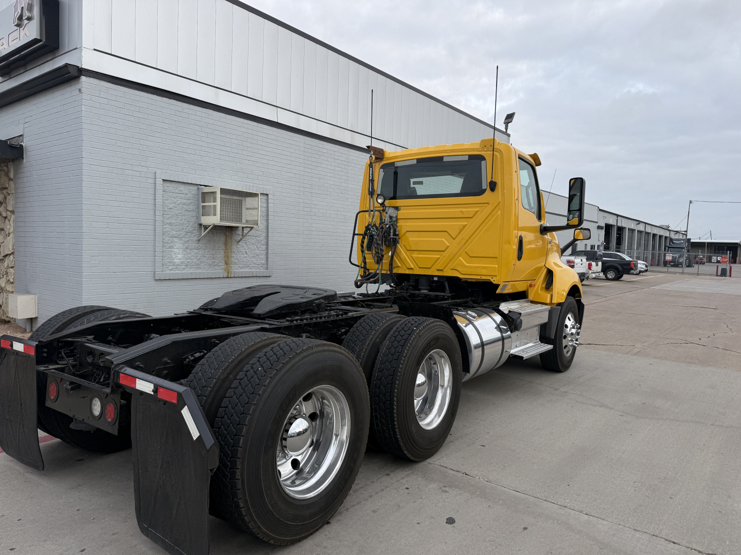 Truck chassis and cab of a yellow 2019 International LT conventional daycab, view showing rear tractor wheels and siderail fuel tank.