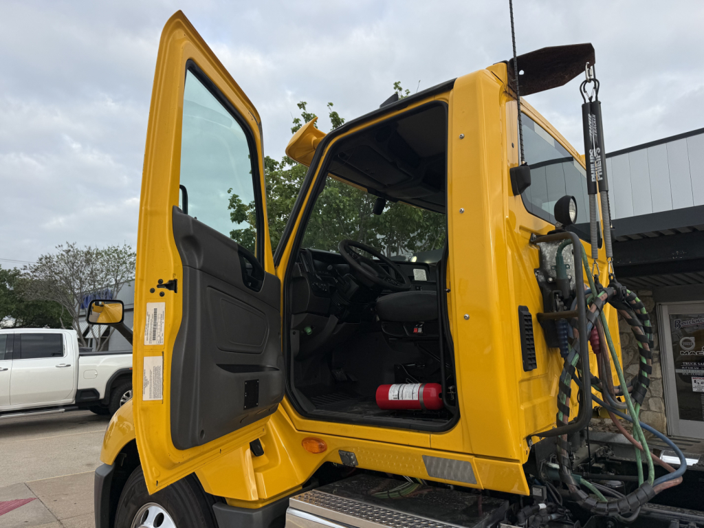 Cab shows interior and open door of a yellow 2019 International LT truck cab with steering wheel and dashboard visible.