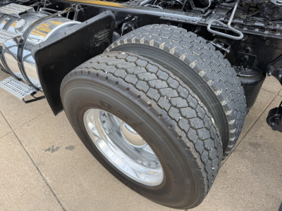 Truck rear dual tires and chassis showing heavy-duty wheel assembly with chrome rims and fuel or air tanks nearby; part of International LT truck.