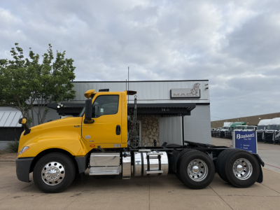 Truck side view showing a bright yellow 2019 International LT cab with a beavertail 6x4 chassis and twin rear axles. Visible text includes VIN plate with 3HSDZTZR3KN739956 and a Brakes sign in the background.