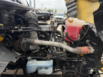 Engine bay of a 2019 International LT conventional daycab showing coolant reservoir, power steering/ hydraulic lines, and various hoses.