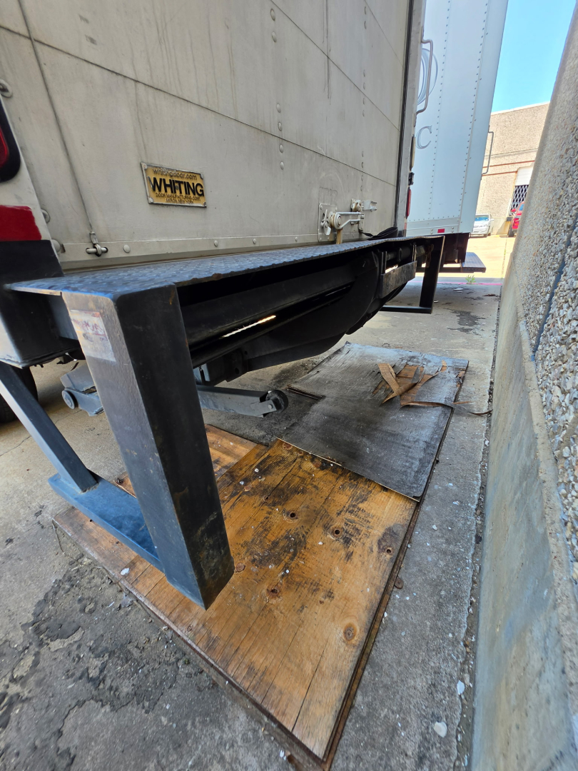 Trucks/box truck rear view showing loading dock with wooden platform and metal frame, mid-section of trailer undercarriage visible.