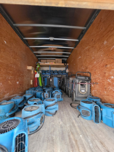 Inside cargo area of a 2016 Chevrolet Express 3500 box truck showing multiple blue portable air movers/vacuum cleaners and equipment stacked along wooden walls.