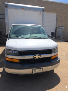 Chevrolet Express 3500 box truck front view showing Chevrolet emblem grille, headlights, orange turn signals, and box truck cargo area in background. License plate area visible.