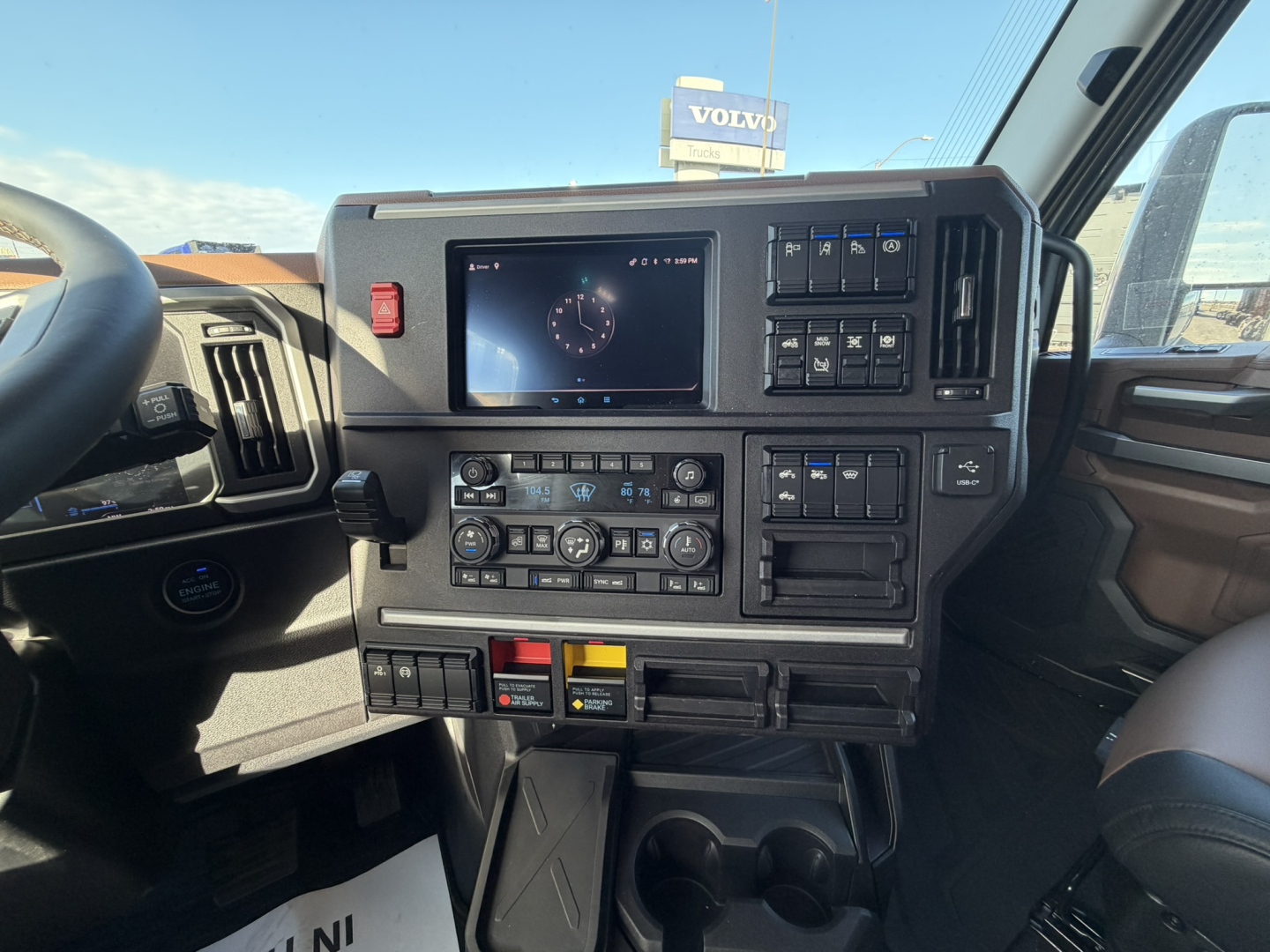Dashboard interior of a Mack PR64T76H truck showing a touchscreen display, control panels, climate controls, and cup holders.