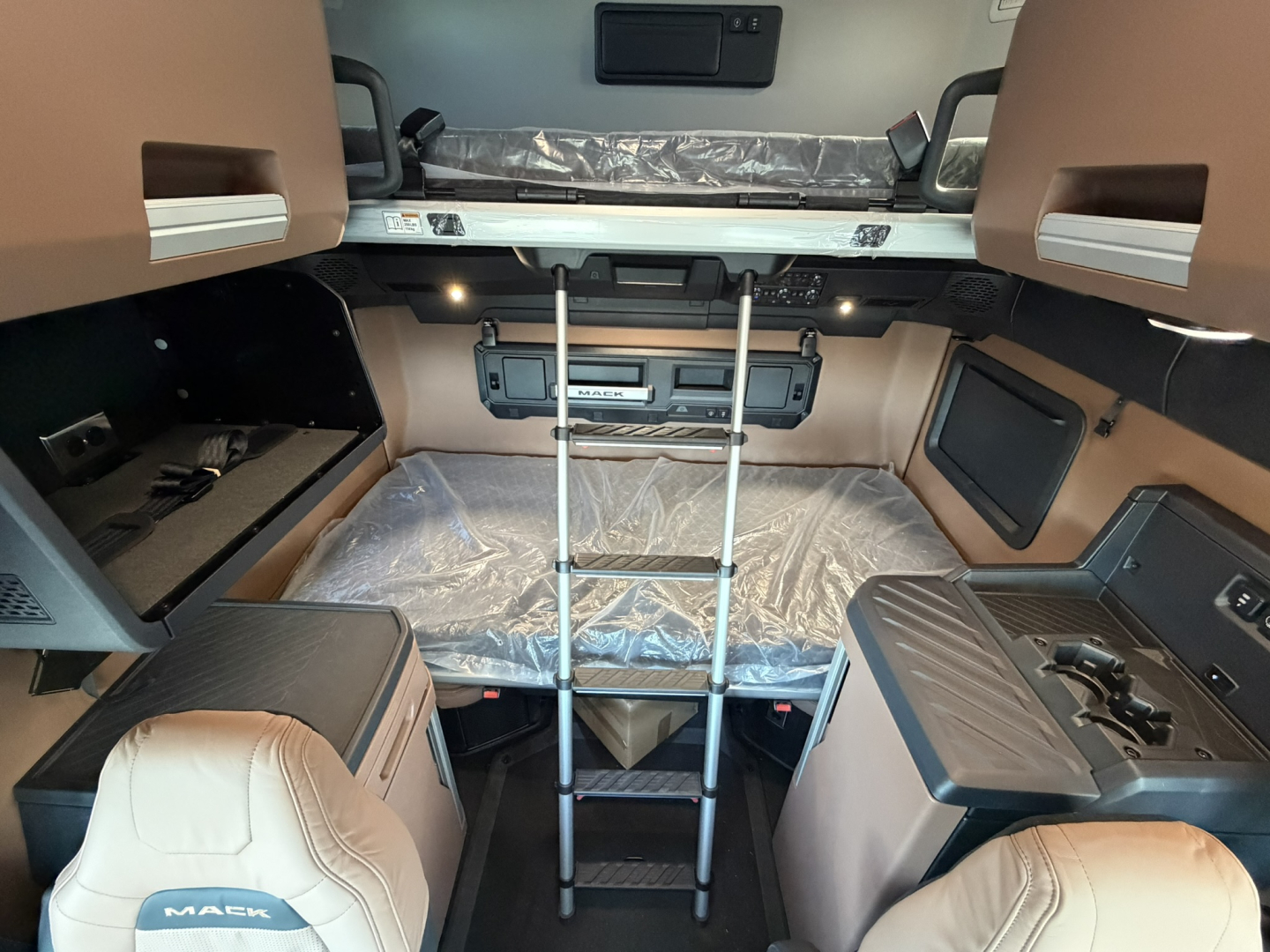 Mack PR64T76H sleeper cab interior showing ladder to upper bunk and side storage compartments.